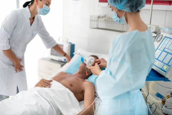 Enfermera sosteniendo equipo respiratorio mientras el médico cuida al paciente — Foto de Stock