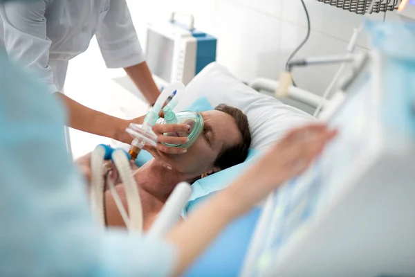 Médico poniendo máscara de oxígeno en el paciente en estado crítico — Foto de Stock