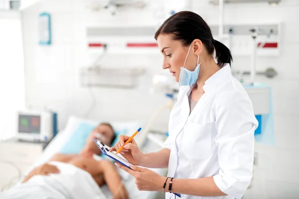 Joven médico anotando información sobre el paciente — Foto de Stock