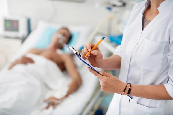 Ärztin hält Klemmbrett und Stift mit Patientin auf verschwommenem Hintergrund — Stockfoto