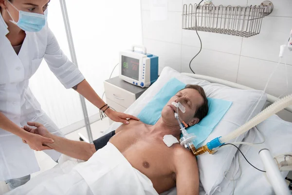 Enfermeira segurando a mão e ombro do paciente na máquina de respiração — Fotografia de Stock