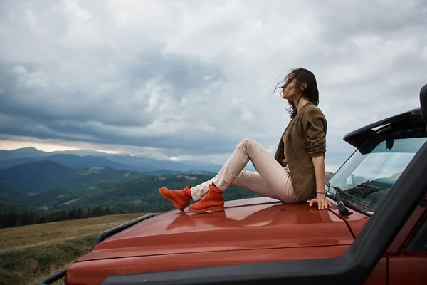 Aangename jonge vrouw liggend op de motorkap van de auto — Stockfoto