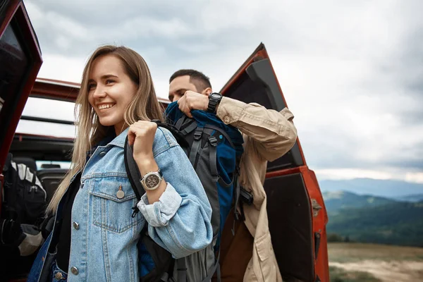 Angenehmer junger Mann hilft seiner Freundin mit dem Rucksack — Stockfoto