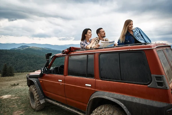 Jóvenes amigos activos usando el mapa de viajes en las montañas —  Fotos de Stock