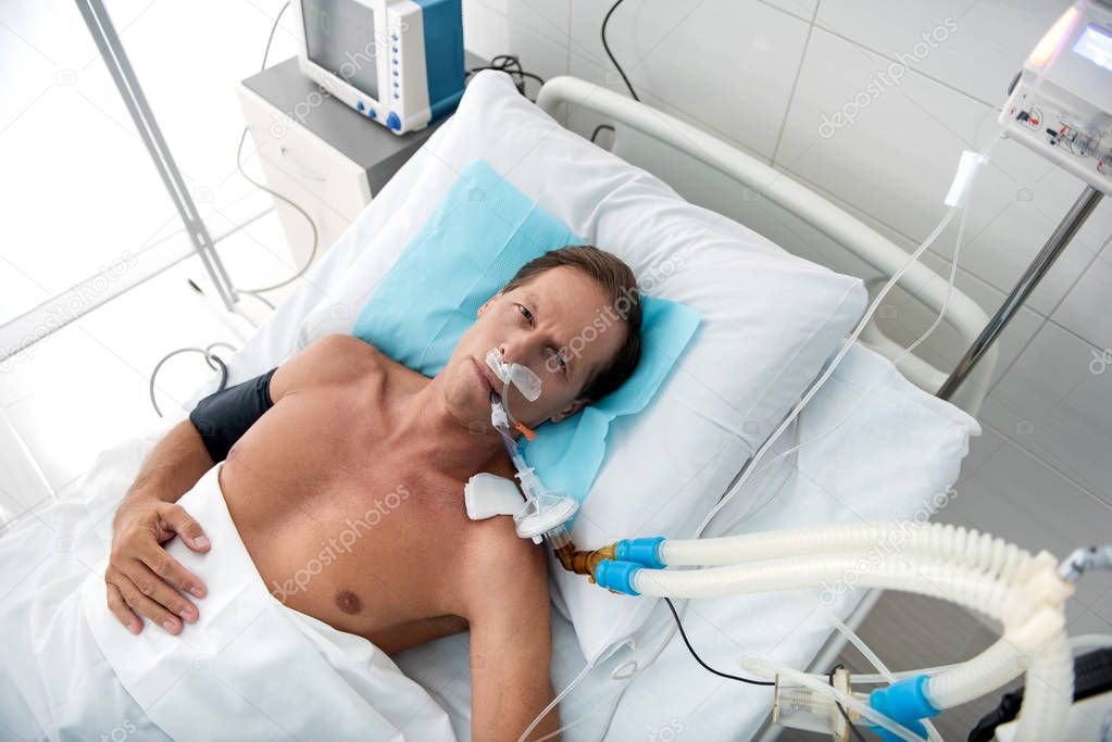 Patient on breathing machine lying in hospital bed after surgery