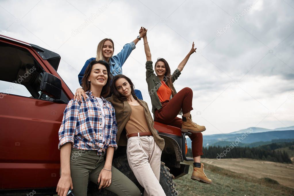 Group of positive young women standing near their car