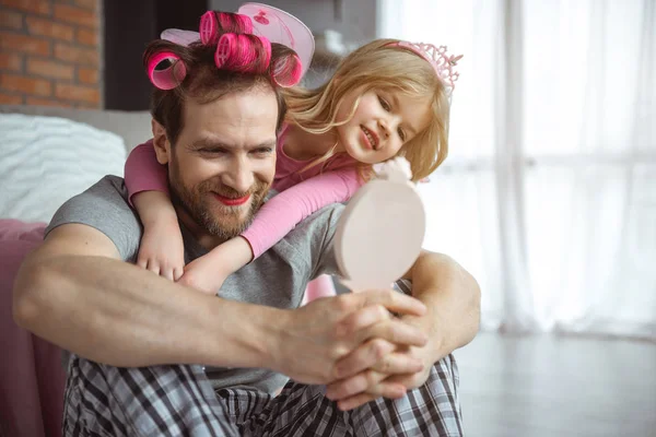 Homem positivo com maquiagem facial olhando para o espelho com filha — Fotografia de Stock