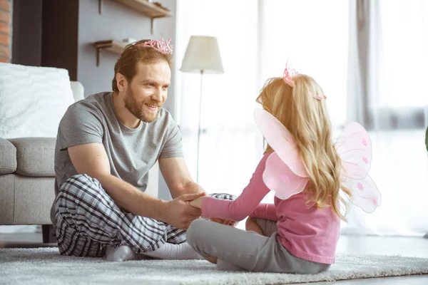 Feliz pai e filha sentados no tapete macio com alegria — Fotografia de Stock