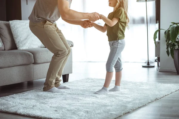 Веселий батько танцює зі своєю маленькою донькою на килимі — стокове фото