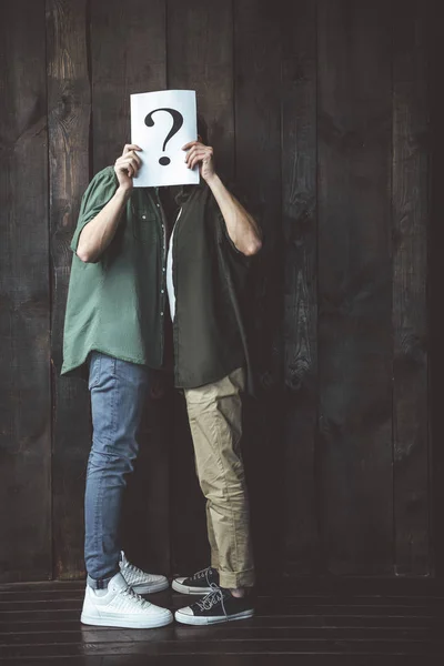 Gay couple covering faces with question sign — Stock Photo, Image