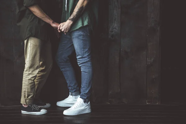 Junges homosexuelles Paar hält Hände auf hölzernem Hintergrund — Stockfoto