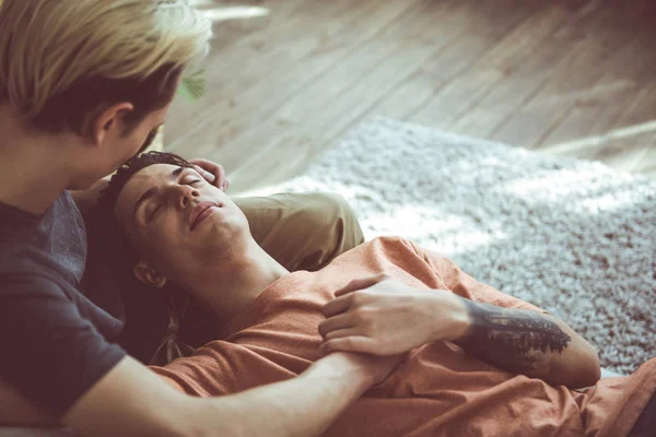 Mladý gay pár odpočívá společně na gauči doma — Stock fotografie