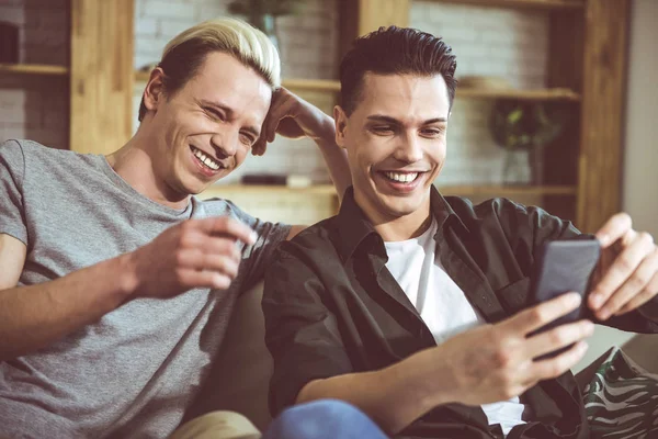 Két fiatal férfi keresi a smartphone képernyő, és nevetve — Stock Fotó