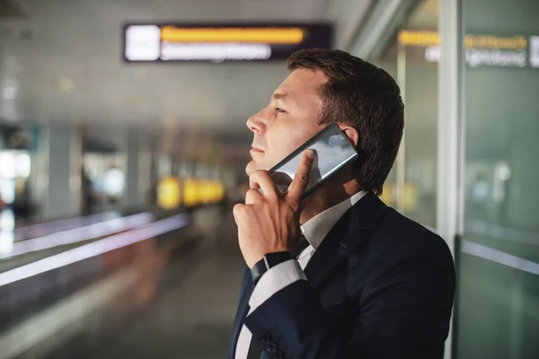 Uomo serio impegnato a parlare al telefono nel corridoio — Foto Stock