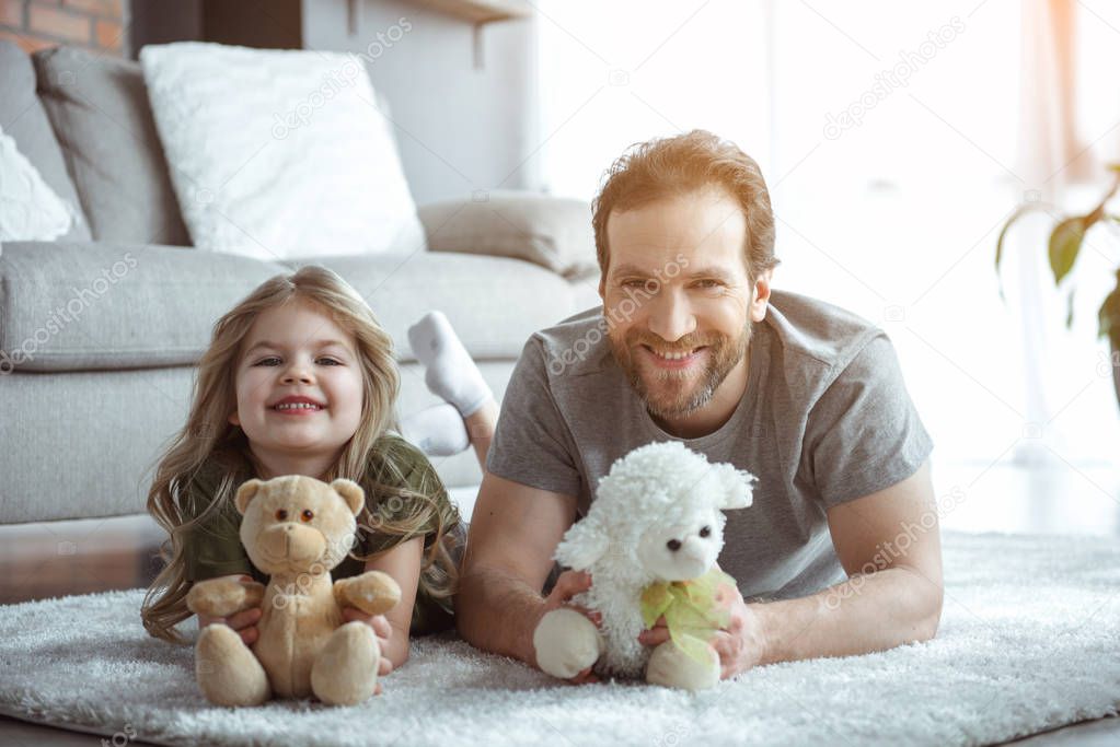 Excited dad and girl playing with teddy bear 
