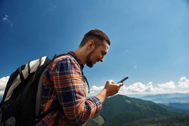 Gülümseyen backpacker smartphone tepe üzerinde kullanıyor