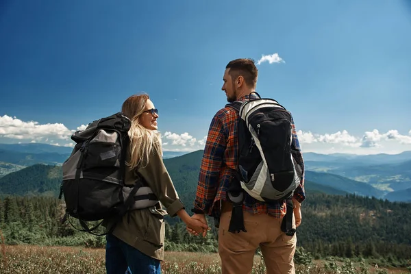 Un homme et une femme souriants marchent ensemble dans les montagnes — Photo