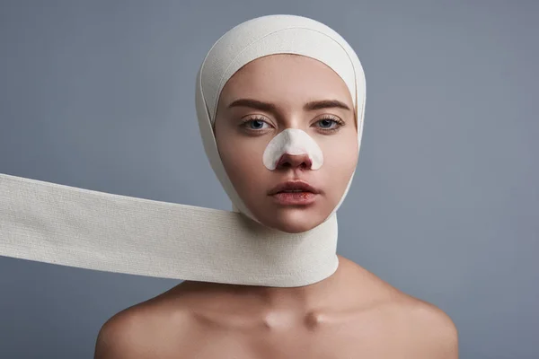 Ernste Frau, die dich ansieht, während du Bandagen und Streifen hast — Stockfoto