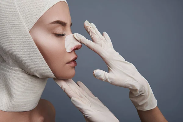 Rustige vrouw met gesloten ogen en handen in handschoenen aanraken haar neus — Stockfoto