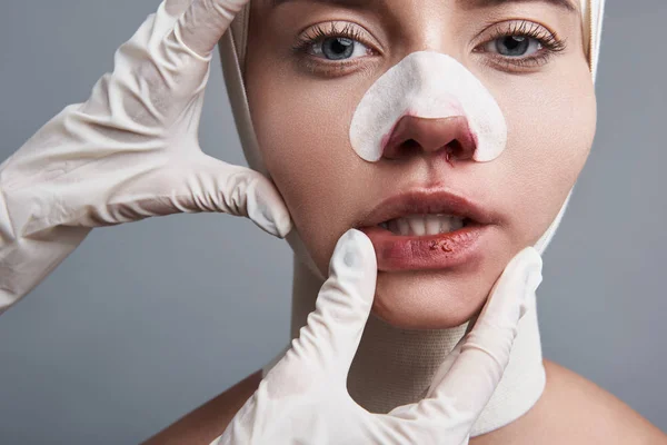 Handen in handschoenen aanraken van de lippen van jonge vrouw en haar tanden onthullen — Stockfoto