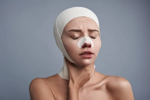 Mujer triste tocándose el cuello mientras se recupera después de una cirugía plástica —  Fotos de Stock