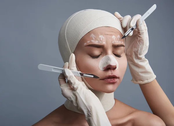 Nerveus dame haar ogen terwijl twee scalpels wordt in de buurt van haar gezicht sluiten — Stockfoto