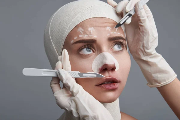 Bang vrouw kijken naar de scalpel terwijl haar chirurg werken — Stockfoto