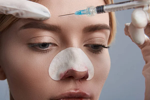 Jonge dame op zoek rustig terwijl ze injectie in haar voorhoofd — Stockfoto