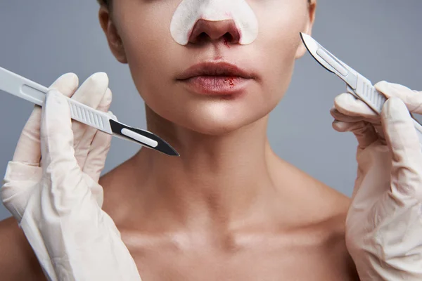 Close-up van twee scalpels in de buurt van het gezicht van jonge dame — Stockfoto