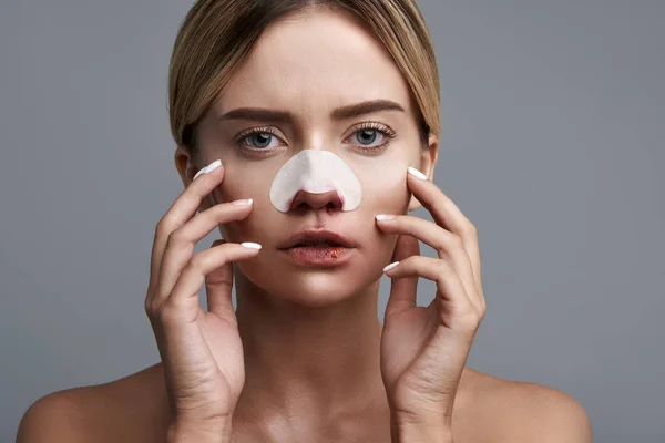 Emotionale Frau berührt ihr Gesicht, während sie eine blutige Nase hat — Stockfoto