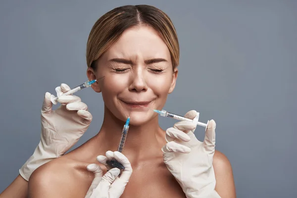 Scared woman closing her eyes while getting three painful injections