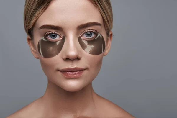 Laconieke portret van een jonge vrouw met behulp van eye patches — Stockfoto