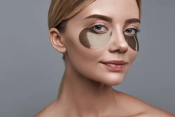 Söt flicka leende och tittar på dig medan du använder eye patches — Stockfoto