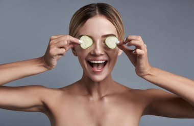 Salatalık dilim gözleri için koyarak ve gülümseyen heyecanlı Bayan