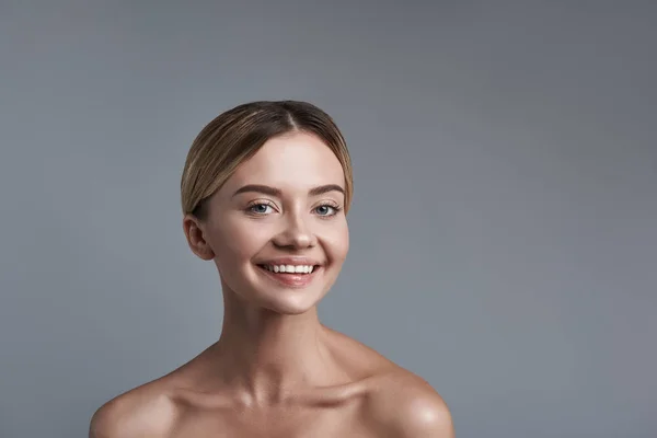 Positieve portret van lachende gelukkige vrouw staande tegen de grijze achtergrond — Stockfoto