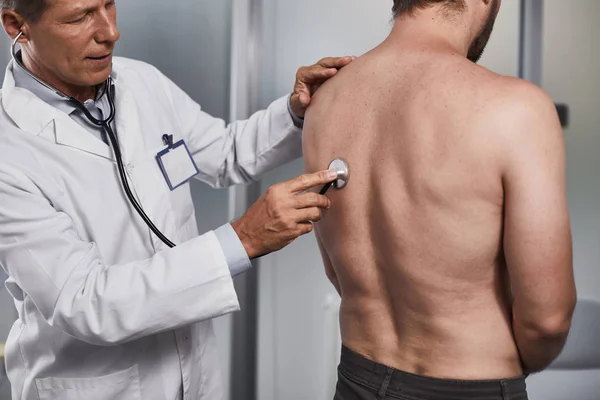 Männlicher Patient wird von erfahrenem Arzt untersucht — Stockfoto