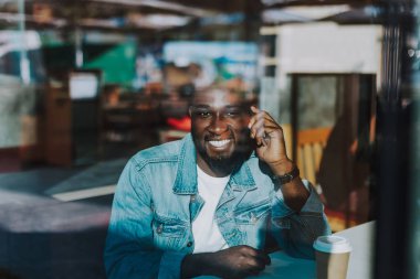 Tek başına oturan adam gülümseyerek ve gülümseyen süre telefonda konuşurken