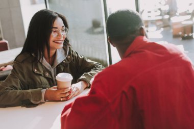 Erkek arkadaşı pencerenin yanında oturan ve kahve içme gülümseyen kadın