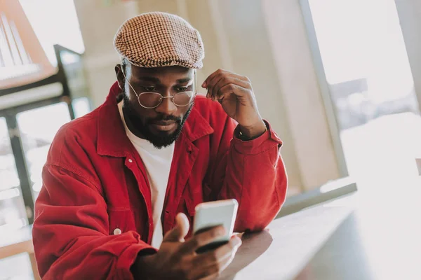 Bebaarde man alleen zitten en kijken naar het scherm van zijn smartphone — Stockfoto