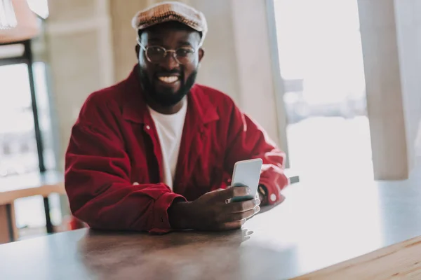 Positieve man zitten met moderne smartphone en op zoek blij — Stockfoto