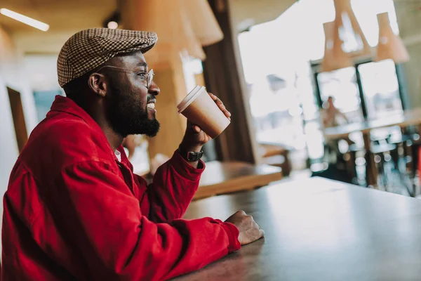 Jonge man die blij terwijl alleen zitten en koffie drinken — Stockfoto