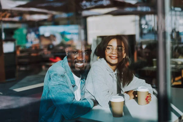 Glücklicher Mann umarmt seine Freundin, während er mit ihr im Café sitzt — Stockfoto