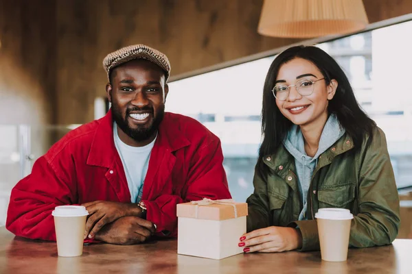 Delighted young people feeling happy while sitting with little present