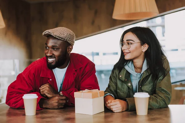 Usmívající se pár sedí v kavárně a při pohledu do dálky — Stock fotografie