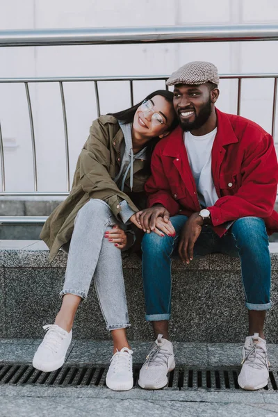 Deleitado joven sonriente pareja internacional sentado juntos — Foto de Stock