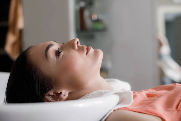 Relaxed woman is having hair washed in salon