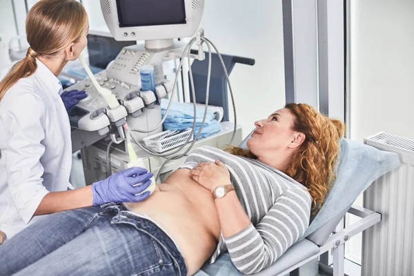 Доктор вивчає зрілу жінку з пристроєм ультразвукового сканера — стокове фото