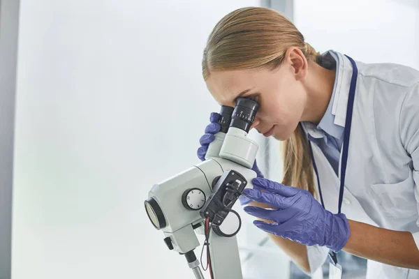 Dokter muda melihat melalui kolposkop di laboratorium — Stok Foto