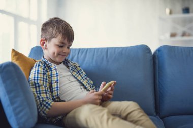 Gülümseyen ve onun smartphone ile evde rahatlatıcı mutlu çocuk