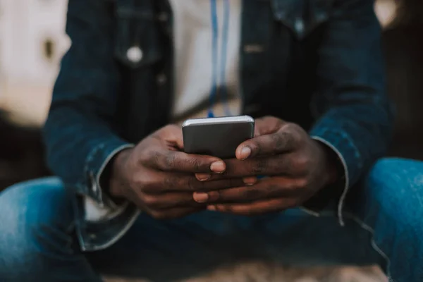 Primer plano de un smartphone en manos de un hombre amro americano —  Fotos de Stock